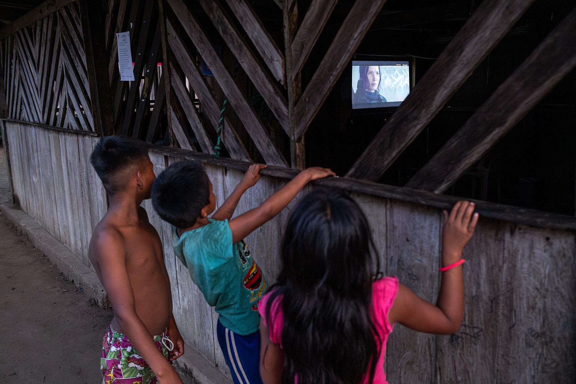 Unos niños ven televisión desde afuera de una casa vecina en la comunidad de Curare, resguardo Curare Los Ingleses. Amazonas, Colombia. Foto: Víctor Galeano.